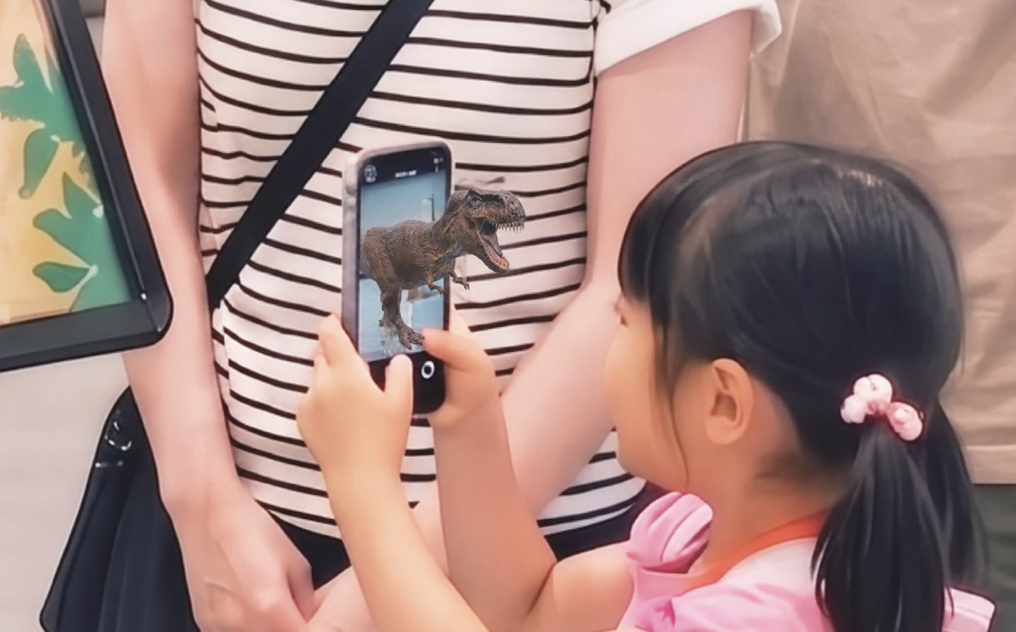 スマホに映ったARの恐竜を見る女の子