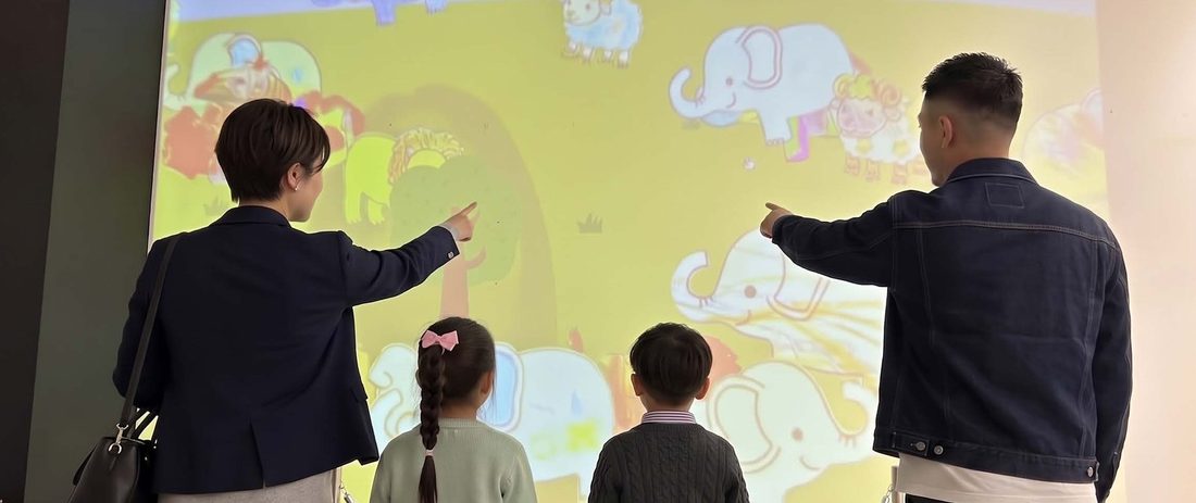 投影されたぬりえを指さす大人と子ども