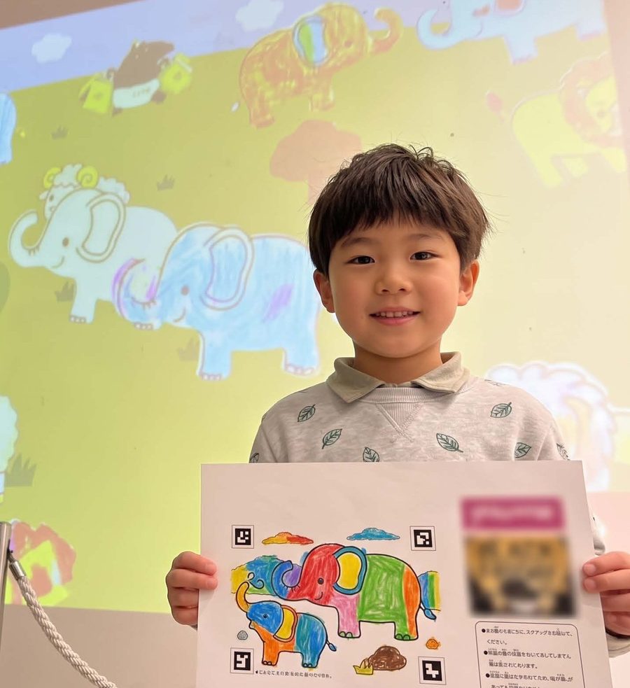 塗った象のぬりえ用紙を掲げる男の子