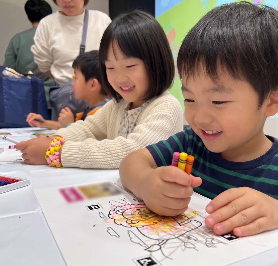 テーブルでぬりえに色を塗る子どもたち