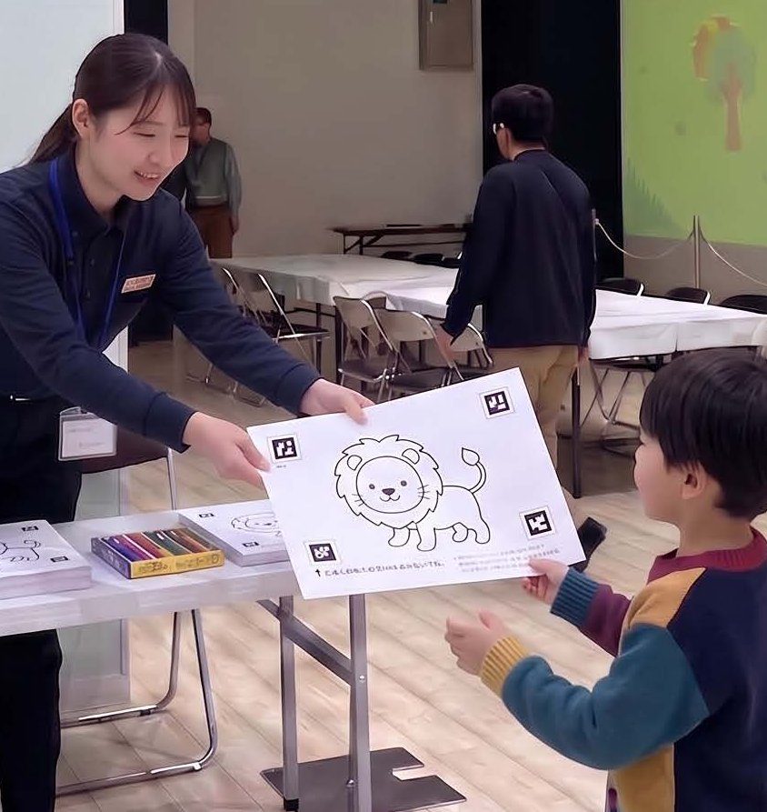受付でぬりえ用紙を受け取る男の子