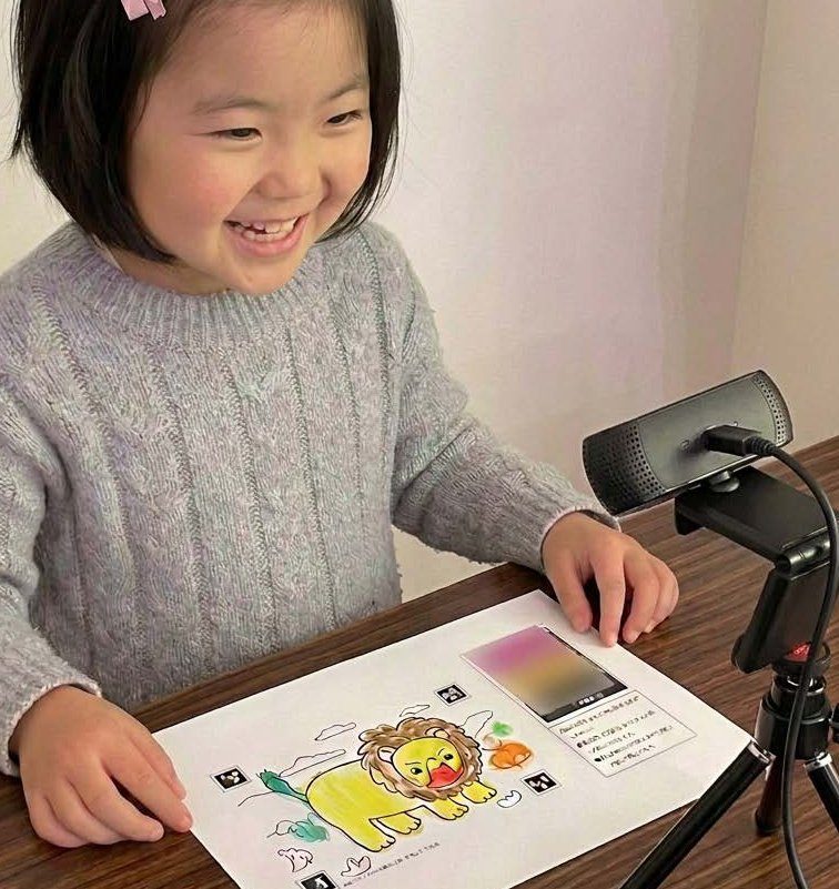 カメラでぬりえを読み込む女の子